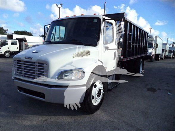 Freightliner BUSINESS CLASS M2 106 dump truck in white with chrome grille and black dump bed side view