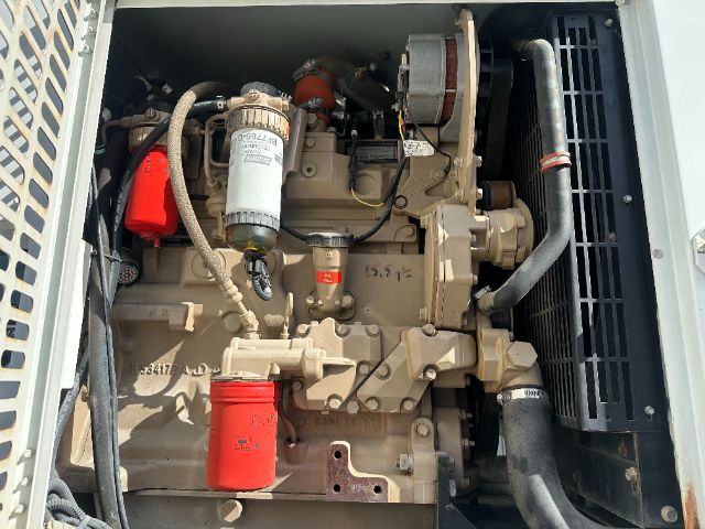 Truck engine bay with beige Cummins/Detroit diesel engine, red oil filter, silver fuel filter, and hoses. Visible labels include a white fuel/water separator canister with black text, red coolant cap, and red rectangular component. Radiator