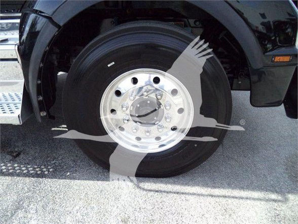 Kenworth T880 wheel and tire close-up showing front hub with polished metal rim and black tire in a truck bed area.