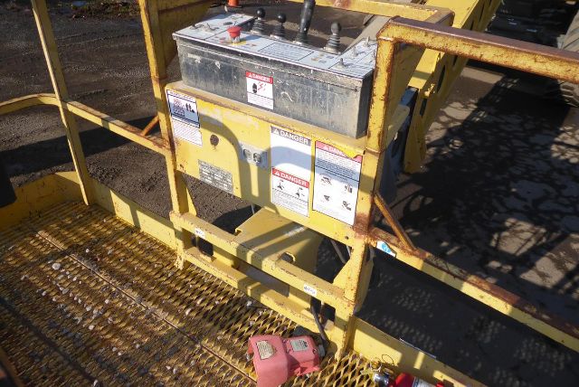 Grove T60 truck crane control panel and yellow lift platform with warning labels and metal grated decking.