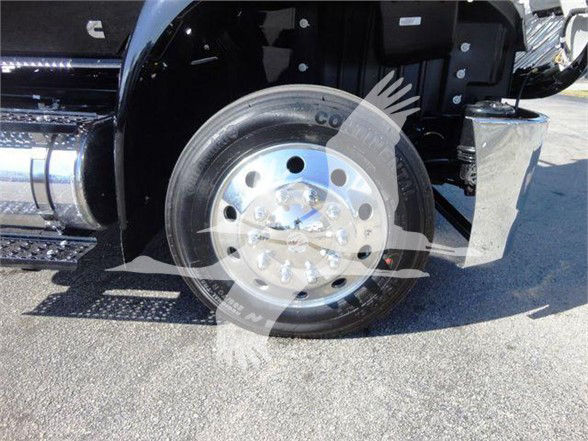 Wheel and front fender of a 2022 International MV truck showing chrome hub, tire, and part of undercarriage.