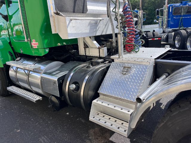 Diamond plate fuel/tool box and air lines beside a green Kenworth T800 tractor unit showing side steps and fuel tanks.