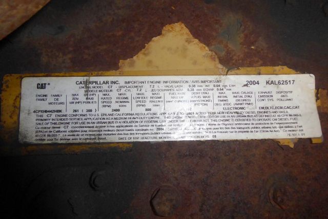 Bus label plate with model and engine information from Caterpillar Inc. warranty/engine label. Text is small and dense across a rectangular sticker.