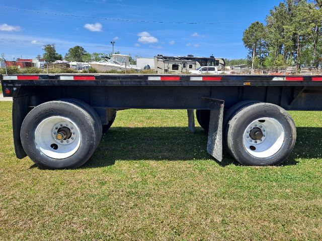 Fontaine flatbed trailer side view showing dual rear wheels and undercarriage with black frame and reflective tape.