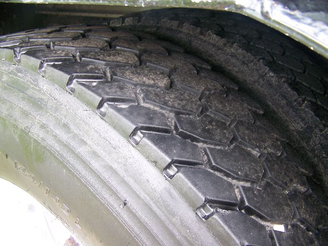 Truck wheel tire close-up showing tread pattern and sidewall with some dirt.