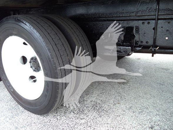 Isuzu NPR HD truck undercarriage showing front wheel and suspension with white rim and black frame.
