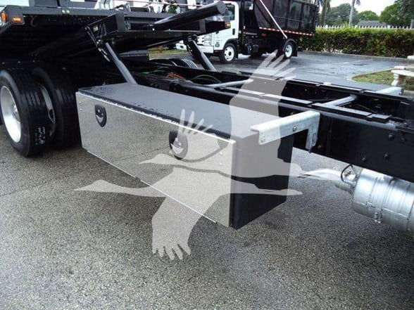 Freightliner truck chassis showing a metallic storage box under the frame with a spare tire mount and hitch area.