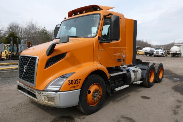 Orange 2019 Volvo VNR64T300 daycab truck with cab lights, 6x4 axle, large grille, VIN sticker and stock number not visible on doors.