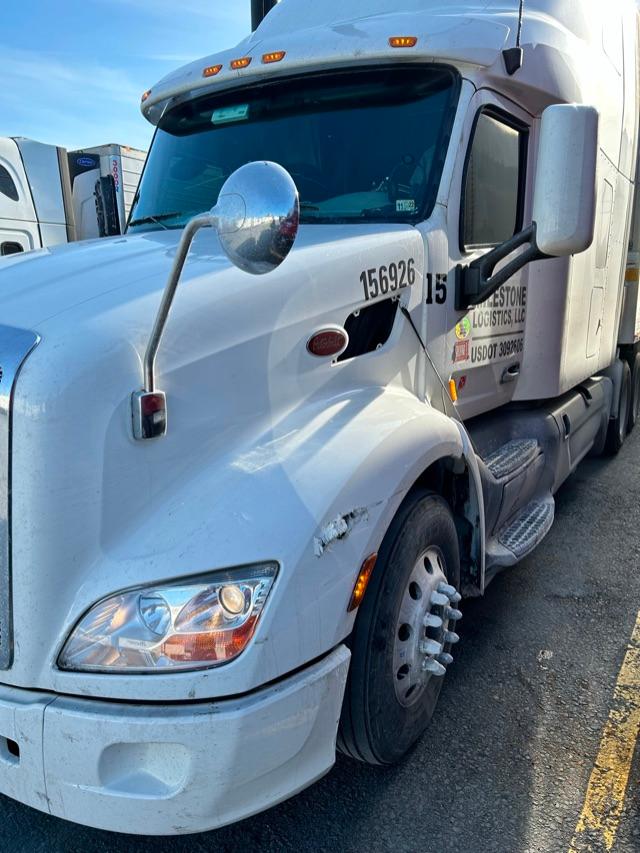 Peterbilt 579 truck side view showing cab, front wheel, and door with numbers and logos.