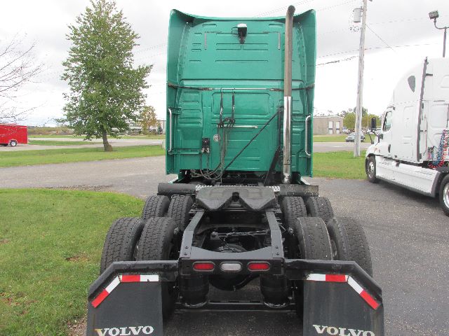 Volvo tractor rear view showing fifth wheel, dual rear axles, green sleeper cab, and rear mud flaps with Volvo logo.