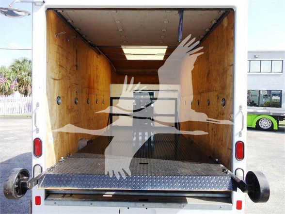 Ford E-350 box truck cargo area with wooden walls, diamond plate floor, rear ramp lowered, interior empty.