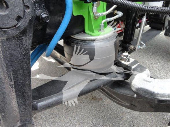 Tow truck front axle area showing hydraulic reservoir and linkage components.