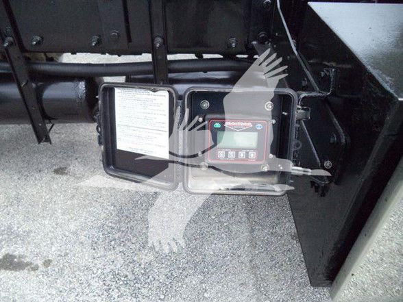 Truck auxiliary equipment showing control panel and open access panel, mounted near the chassis.