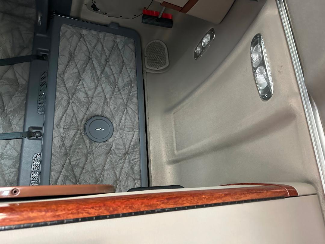 Freightliner Cascadia cabin interior showing floor mat, circular access cap, door panel, and two overhead lights.