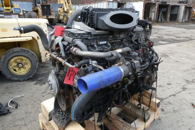 Detroit DD15 engine core on pallet with multiple hoses and fittings, blue intake tube, red tags, forklift in background.