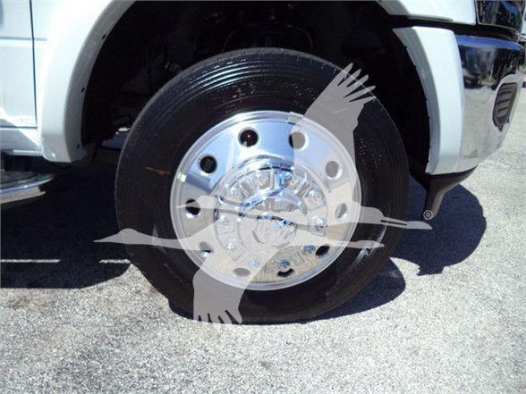 Front left wheel of a white Ram 5500 with chrome hubcap; visible tire and part of fender and bumper.