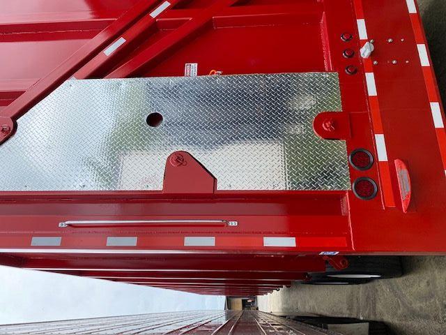 Crush car carrier trailer rear with red sides and diamond plate toolbox, reflective safety stripes, and rear lights.