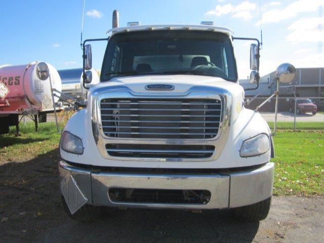 Front view of a white Freightliner M2-112 Columbia truck showing grille, bumper, headlights, and side mirrors.