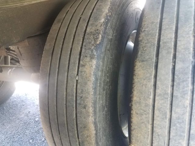 Trailer dual tires with tread wear and dirt, sidewall visible but no legible text.