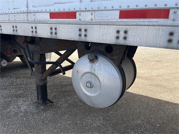 Trailer undercarriage showing a round air reservoir/dryer canister attached to the Wabash dry van chassis.