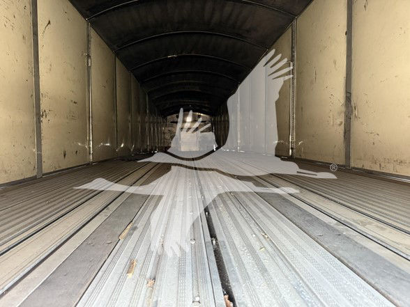 Inside view of a 2022 Reitnouer Big Bubba flatbed trailer trailer bed with ribbed steel floor and sidewalls, empty.