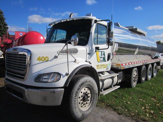 Truck cab with chrome fuel tank trailer, Freightliner M2-112 Columbia, white cab, yellow 400 number on front fender, side tank with reflective stripes, multiple rear axles, tank truck.