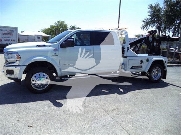 Ram 5500 tow truck side view showing white cab and wheel-lift with visible decals and equipment.