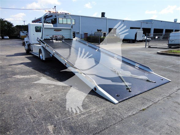 2022 Hino 268A tow truck with a long, lowered metal flatbed in a parking lot