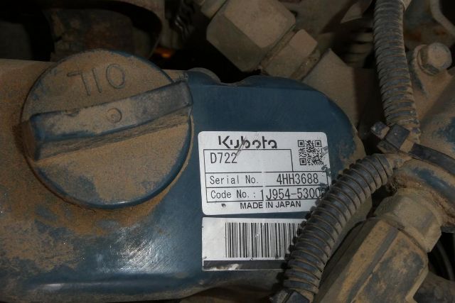 Kubota engine cover with label reading D72? and serial/Code No. 4JH3688 on a blue engine bay, surrounding wiring harnesses and dust.