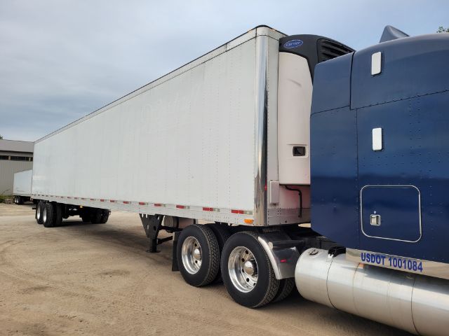53' utility reefer trailer attached to a blue semi truck, side view showing tandem axles and refrigeration unit at the front.
