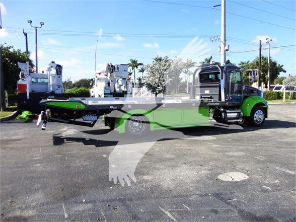 2022 Peterbilt 337 tow truck side view with green and black paint, carrier bed and crane equipment visible.