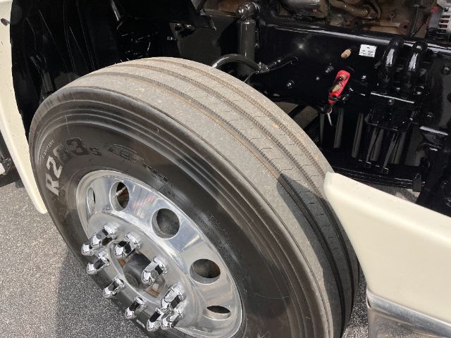 Front wheel and suspension area of a Freightliner Cascadia 125 truck showing large dual rear? single front wheel with chrome rim and black tire, alongside chassis components.