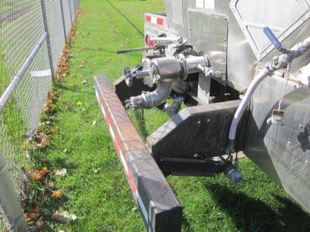 Truck rear with metal framework and hydraulic lines; visible pipes, valves, and a rectangular bumper.