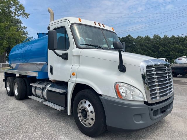 2013 Freightliner Cascadia sewer service truck with blue tank attached. Cab shows large chrome grille, black mirrors, orange clearance lights on roof, and side steps.