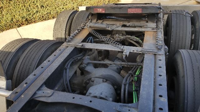 Truck chassis and fifth-wheel area of a 2013 Freightliner Coronado tractor showing frame rails, driveshaft, and air lines.