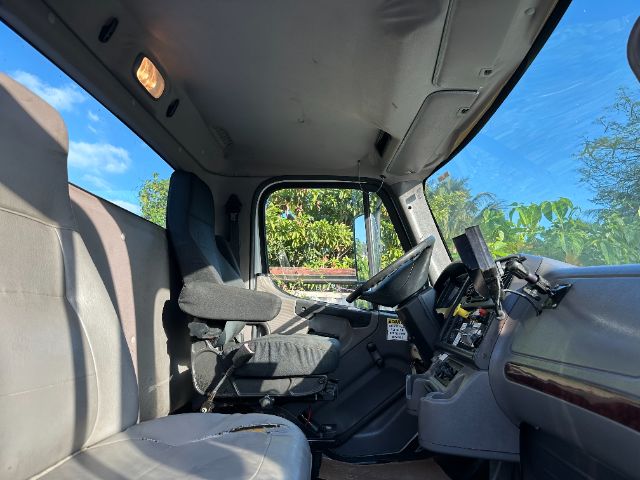 Cab interior of a 2014 Freightliner M2 truck showing the driver seat, steering wheel, dashboard, and passenger bench seat.