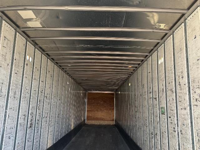 Inside of a utility trailer with bare metal sidewalls and a wooden rear door; empty cargo area.