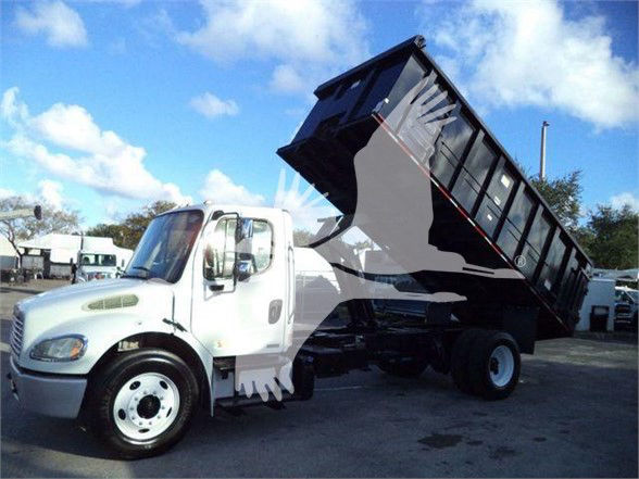2012 Freightliner Business Class M2 106 dump truck with raised black dump bed and white cab.