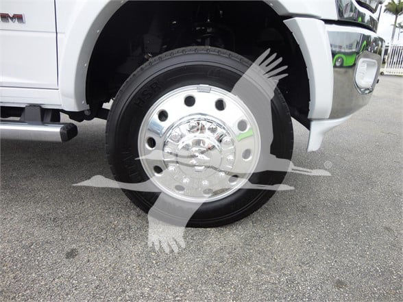 Front wheel and chrome hubcap of a white 2023 Ram 5500 HD SLT with large tire and wheel well.