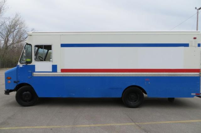 Side view of a 2000 Freightliner MT35 step van with blue lower body, white upper body, and red and blue stripes.