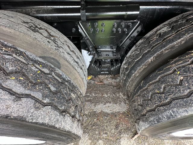 Dual rear truck tires with mud and debris, undercarriage showing a green chassis component between the duals.