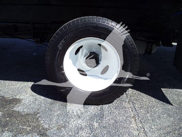 Ford E450 box truck wheel showing black tire and white steel rim with wheel cover.