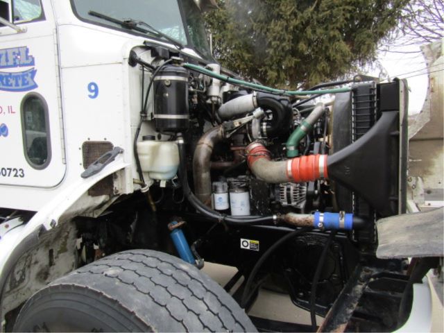 Truck engine bay of a 2003 Peterbilt 330 with visible hoses, radiator, air filter housing, coolant reservoir, and front wheel in view.