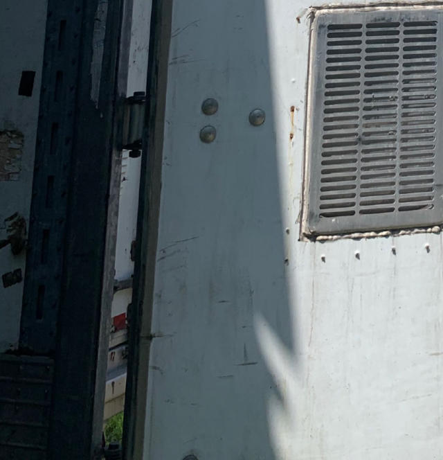 Trailer exterior with vented panel and riveted metal surface, showing a portion of the side and door frame.
