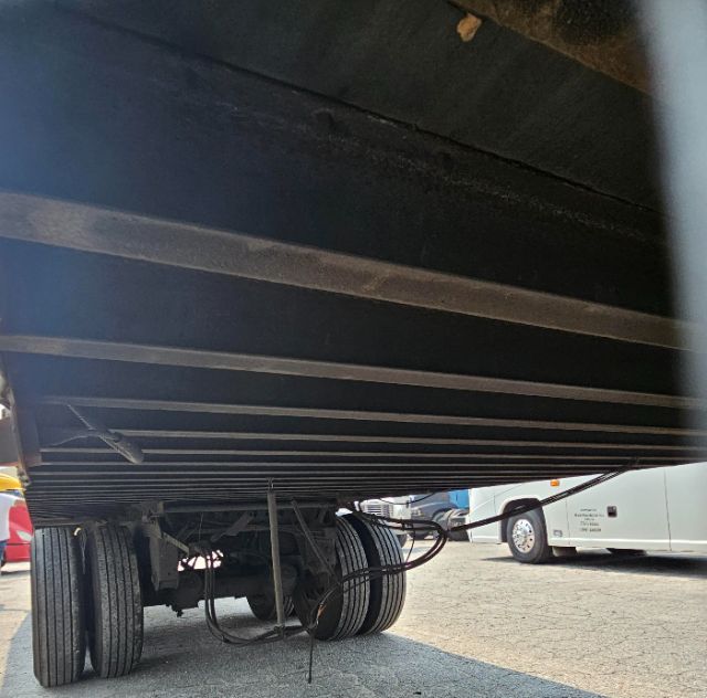 Trailer underside showing dual rear axles and suspension components with wheels visible.