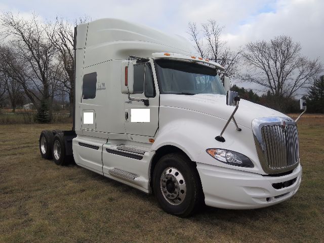 2010 International ProStar conventional sleeper semi-truck parked on grass with white cab, dual rear axles, and chrome grille.
