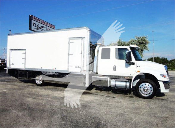 Truck bay image showing a white International MV tow truck with a large cargo box and cab, side mirrors, and chrome fuel tank.