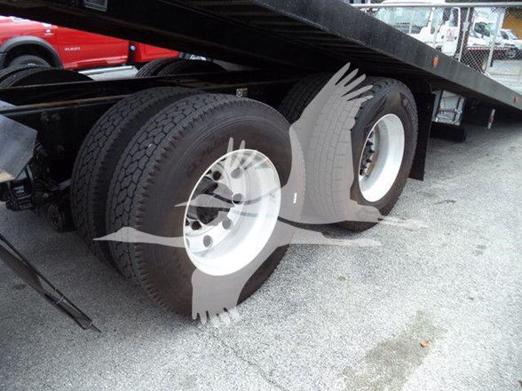 Rear dual-axle truck wheels and frame with a flatbed trailer underneath; no legible labels or text visible on components.