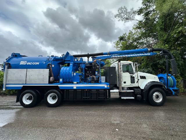 Vacuum truck with blue VAC-CON unit mounted on a white Mack GU713 chassis, side view showing hoses and equipment
