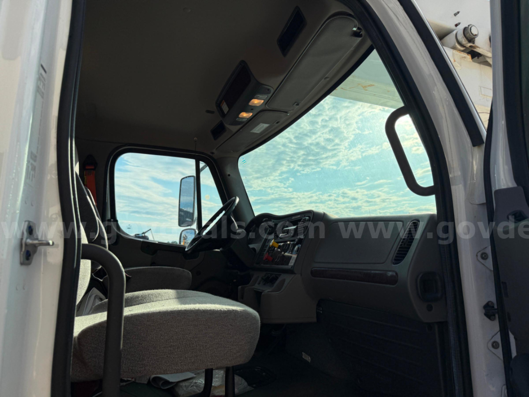 Truck cab interior of a 2020 Freightliner TEREX TC-55 with gray fabric seats, steering wheel, dashboard, and overhead console.